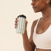 Femme tenant un mug isotherme Qwetch rayé vert tilleul et blanc de Du Bruit dans la Cuisine, en acier inoxydable